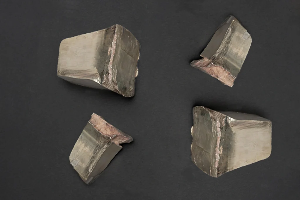 Four rough pieces of raw silver bullion chunks with textured edges displayed on a dark gray surface.
